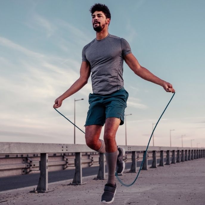 homme saute avec corde à sauter bleue sur un trottoir