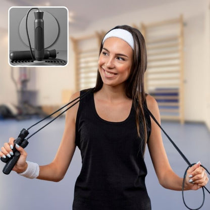femme tient corde a sauter noire autour de son cou dans une salle fitness