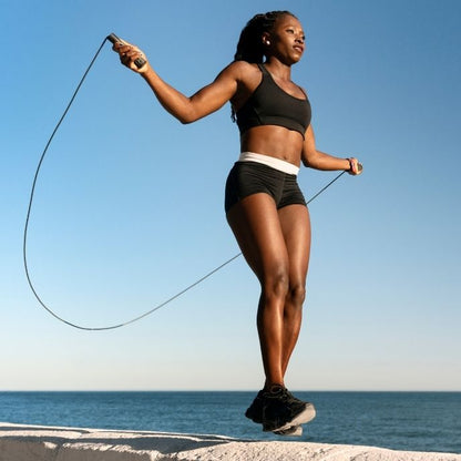femme saute avec corde a sauter au bord de la plage