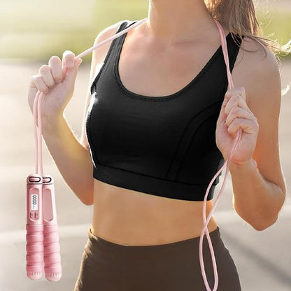 Femme sportive tenant une corde a sauter rose prête à commencer son entraînement de fitness