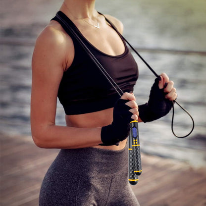 Jeune femme sportive en tenue de fitness tenant une corde à sauter connectée prête pour sa séance d'entraînement cardio à la maison
