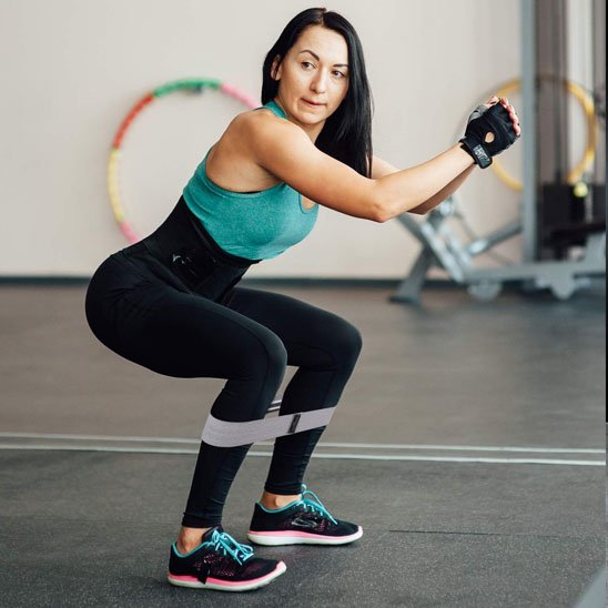 elastique musculation pour cuisses utilisé pendant un squat pour tonifier les jambes et les fessiers