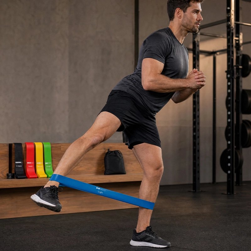 homme utilise elastique sport bleu entre ses deux chevilles en position debout