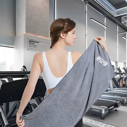 femme avec haut blanc tient serviette de sport grise derrière son dos