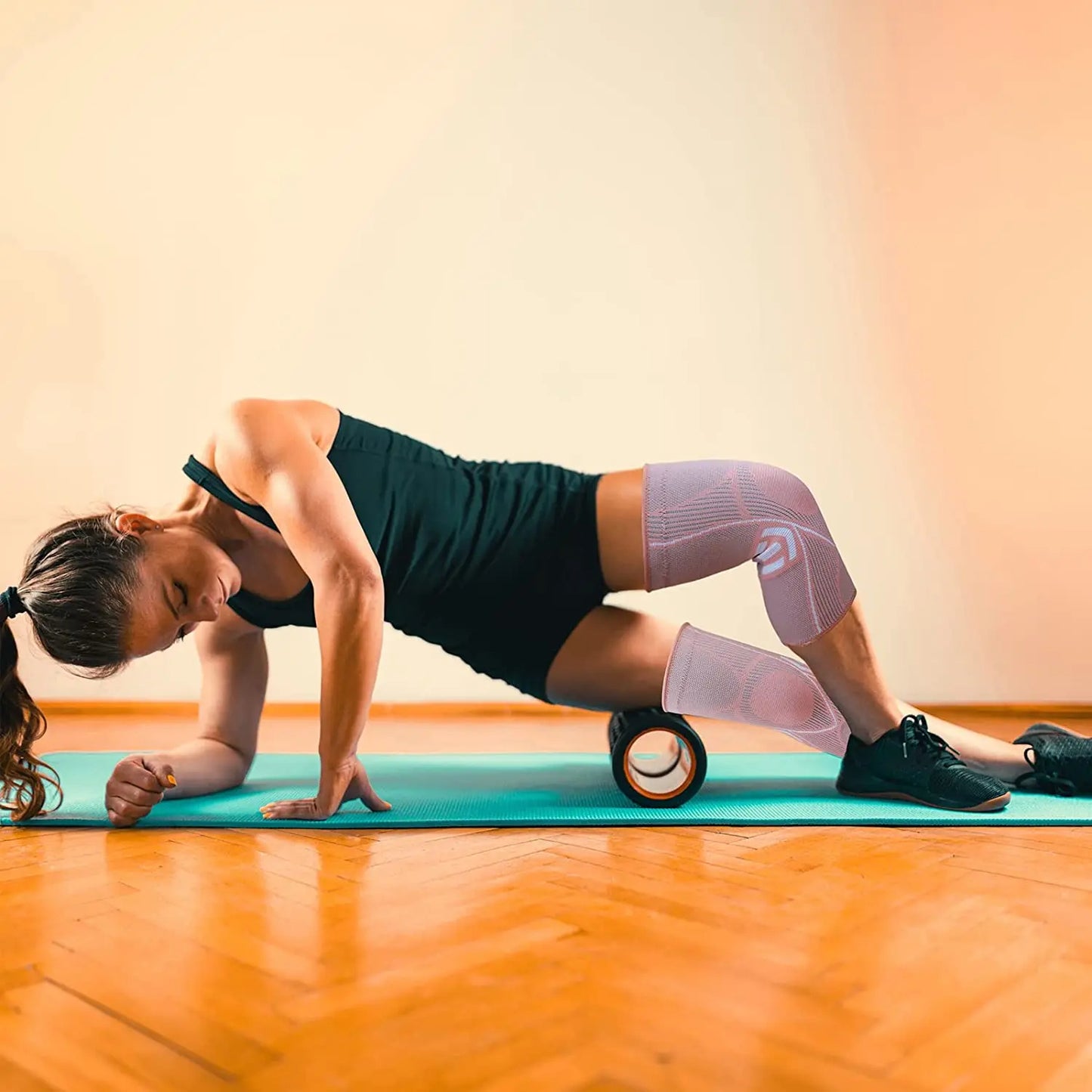 femme-sur-tapis-portant-genouillère-relaxe-sa-jambe-avec-rouleau