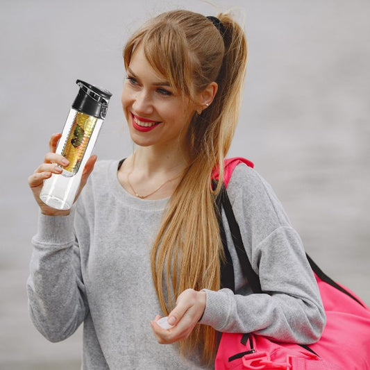 Jeune femme souriante avec sac de sport tenant une gourde plastique noire infusée de fruits