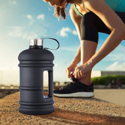 Personne sportive en extérieur s apprêtant à courir au coucher du soleil avec une grande gourde pour le sport noire posée à côté