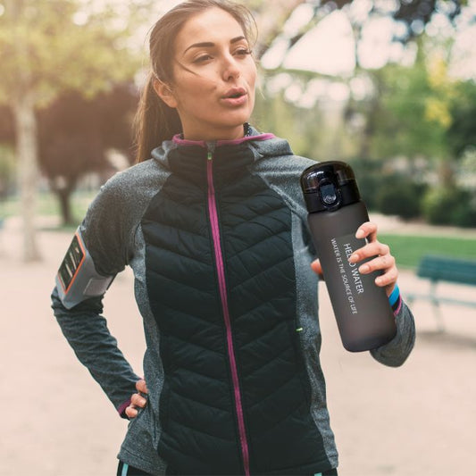 femme tient gourde pour le sport noire a la main dans un parc