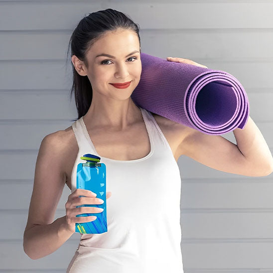 femme tient à la main gourde pour le sport et tapis de gym
