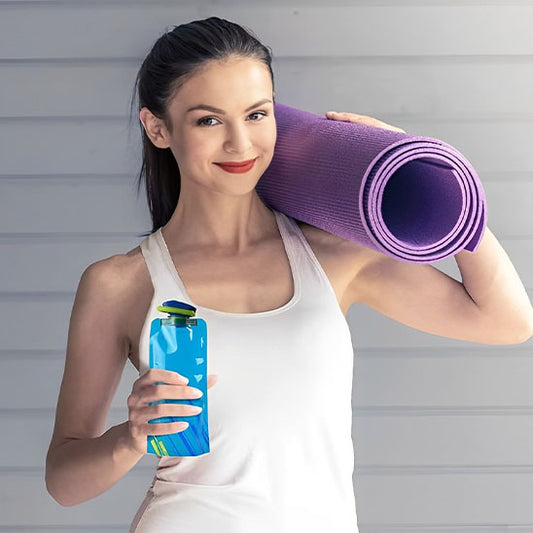 femme tient à la main gourde pour le sport et tapis de gym