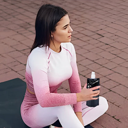 femme tenant gourde pour le sport noir à la main assise sur tapis de yoga