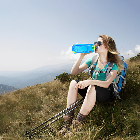 femme assise sur montagne boit de gourde pour le sport bleue