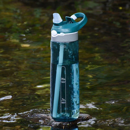 gourde sport bleue posé sur une roche dans un lac