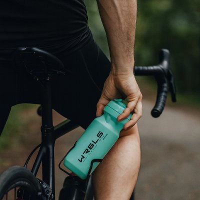 cycliste sur son vélo tient gourde sport vert à la main
