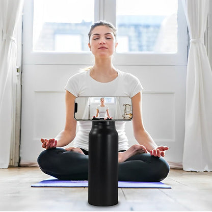 femme fait du yoga avec gourde sport noire et un telephone attaché à la gourde par aimant en face d elle