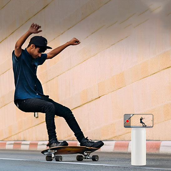 homme fait du skate avec gourde sport blanche et un telephone attaché à la gourde par aimant en face de lui
