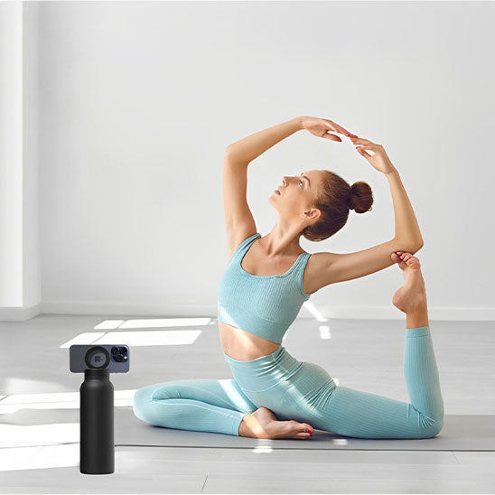 femme fait du yoga avec gourde sport noire et un telephone attaché à la gourde par aimant en face d elle