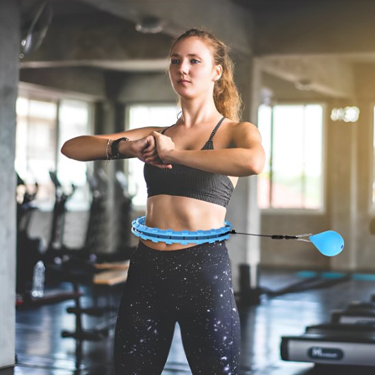 Hula hoop fitness utilisé par une femme en salle de sport pour un entraînement cardio complet et ludique