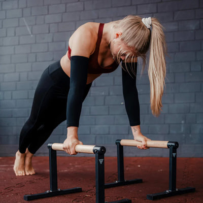 femme-portant-manchon-de-compression-en-position-de-pompes-sur-deux-barres