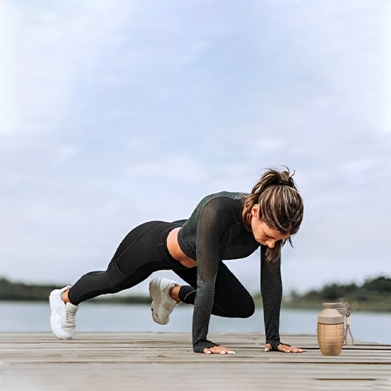 Femme sportive faisant des exercices au sol avec un protein shaker à côté d elle sur une terrasse en plein air