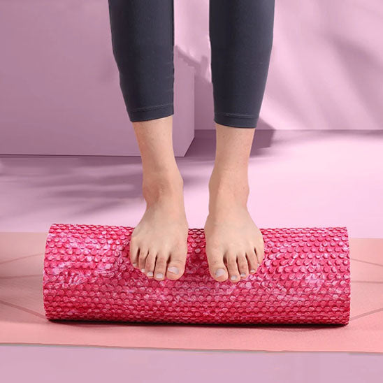 Pieds en équilibre sur un rouleau massage rose pour un exercice d'étirement
