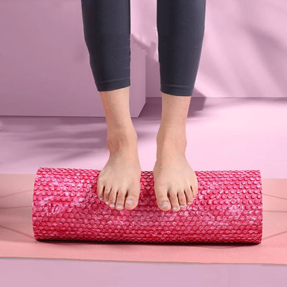 Pieds en équilibre sur un rouleau massage rose pour un exercice d'étirement