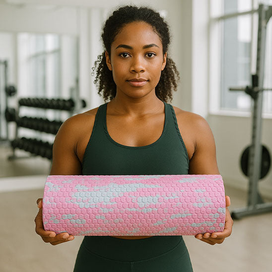 Femme tenant un rouleau massage rose devant elle dans une salle de sport