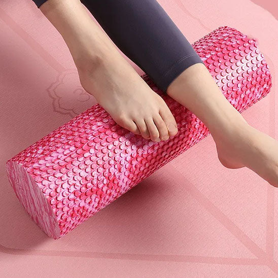 Femme utilisant un rouleau massage rose sous la voûte plantaire pour détendre ses pieds