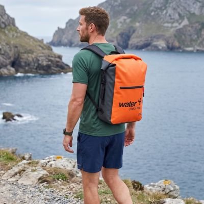 homme porte sac à dos étanche orange sur son dos dans une montagne