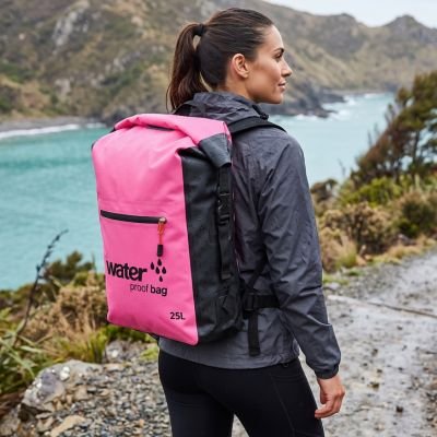 sportive porte sac à dos étanche rose sur son dos au bord d un lac