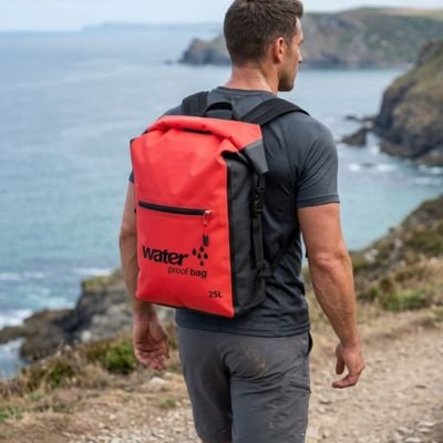 homme porte sac à dos étanche orange sur son dos au bord de la plage