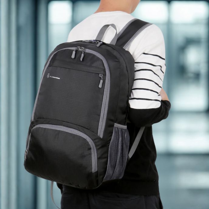 Personne de dos portant un sac a dos pour sport noir à plusieurs compartiments avec poches latérales en filet