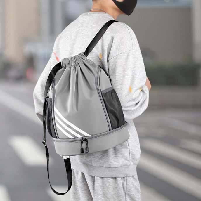 homme avec sac à dos sport gris traverse la rue