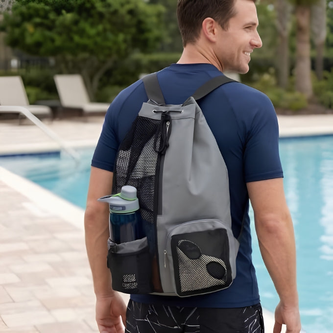 homme porte sac de piscine gris et t-shirt bleu au bord de la piscine