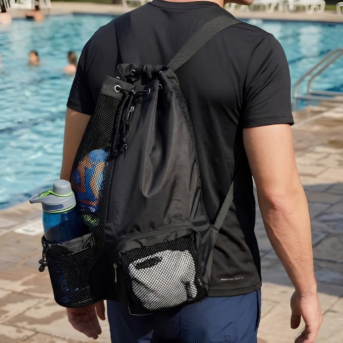 homme porte sac de piscine noir et t-shirt noir au bord de la piscine