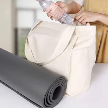 femme entrain de remplir son sac de sport femme avec ses affaires et son tapis de yoga a coté du sac