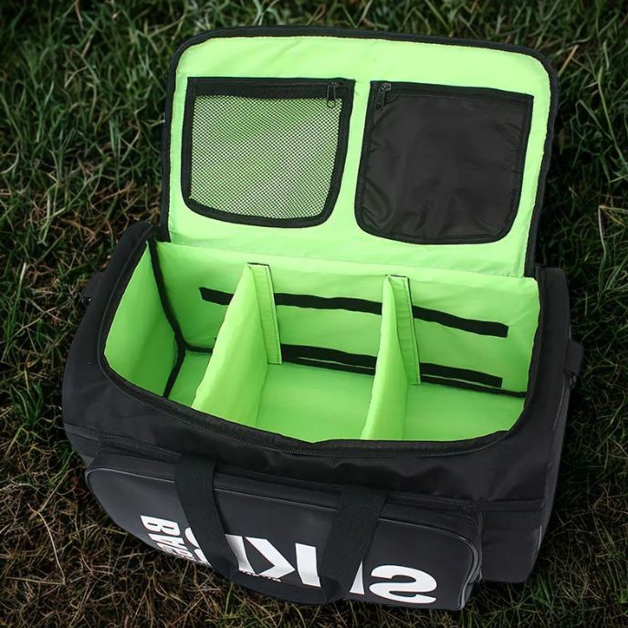 sac de sport fitness noir ouvert pour montrer les différents compartiments posé sur gazon