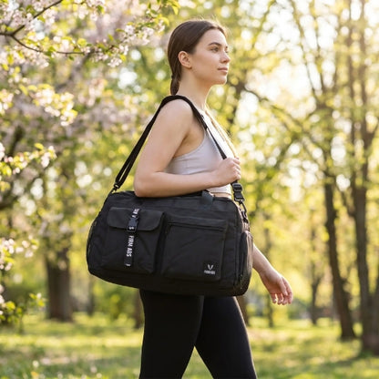 femme sportive habillée en blanc avec sac de sport fitness noir sur son épaule dans un parc