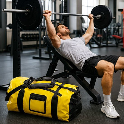 sac de sport fitness jaune placé près d’un homme faisant du développé couché à la salle de musculation