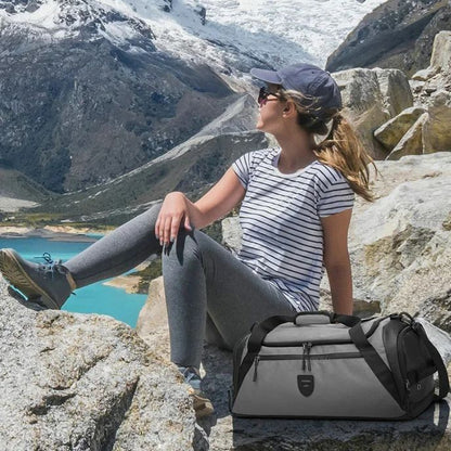 Femme en tenue de randonnée assise sur un rocher face à un lac de montagne avec un sac de sport gris à ses côtés