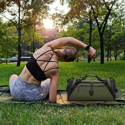Femme en tenue de fitness s étirant dans un parc avec un sac de sport vert posé sur l herbe