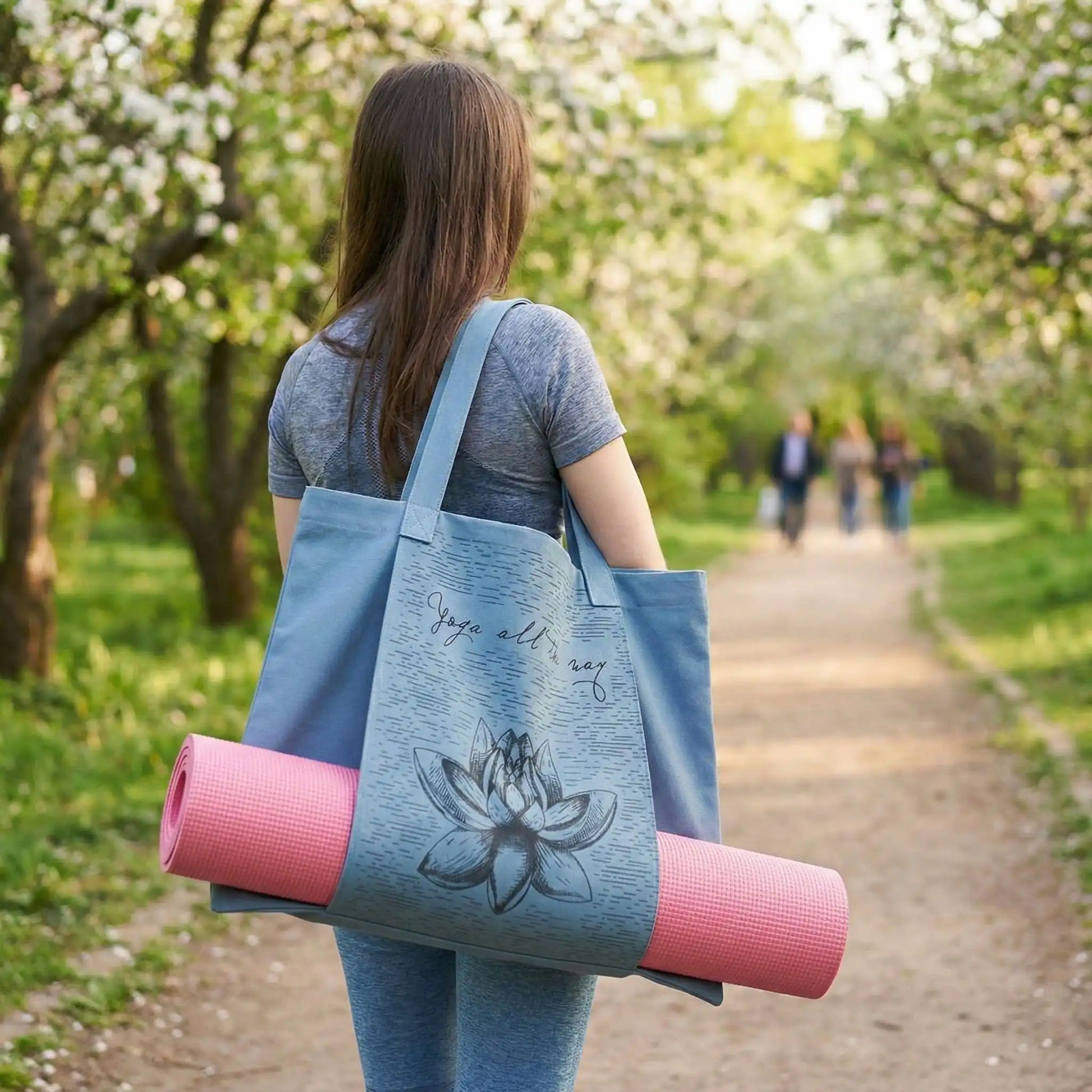 femme portant sac yoga bleu sur son épaule marchant dans un parc