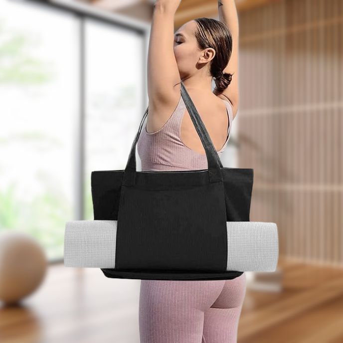 femme porte sac yoga noir sur son épaule avec tapis de yoga dans les manches latérales du sac dans sa chambre