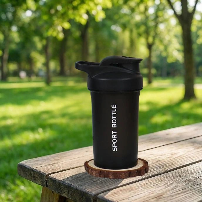 shaker proteine noir miniboost posé sur une table dans un parc