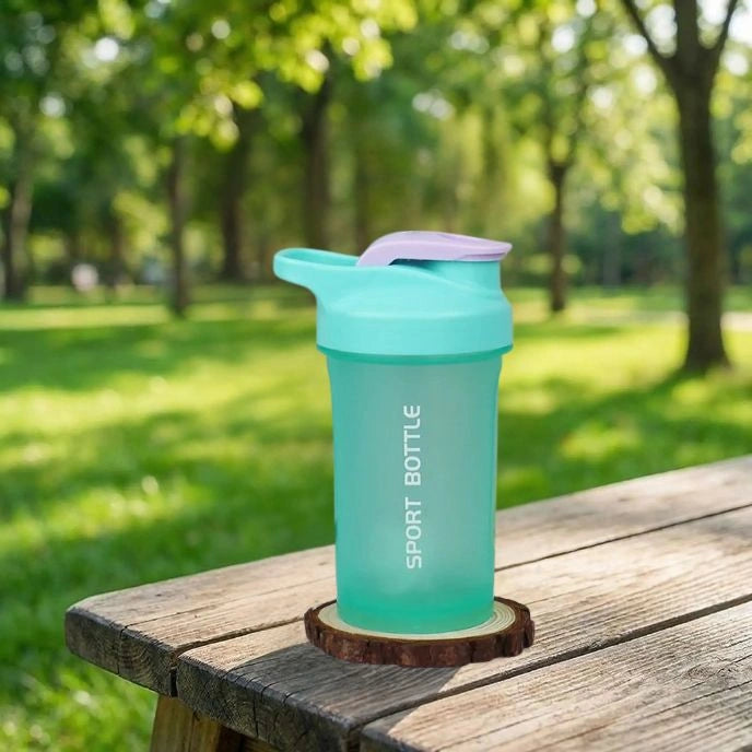 shaker proteine vert miniboost posé sur une table dans un parc