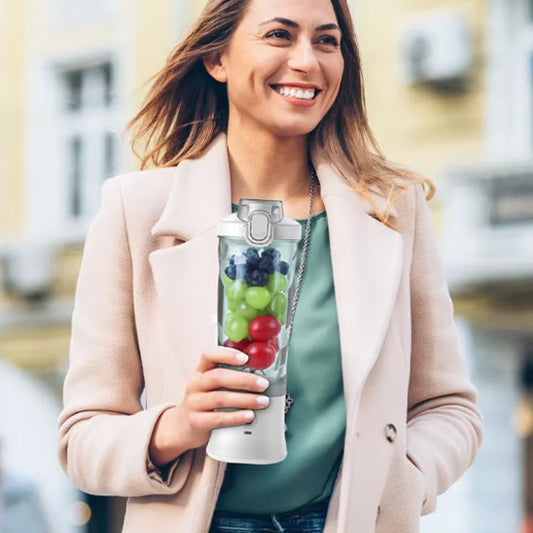 Jeune femme souriante en extérieur habillée élégamment tenant un shaker rempli de fruits pour une boisson detox