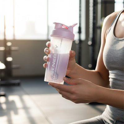 femme tient shaker proteine rose à la main dans une salle fitness