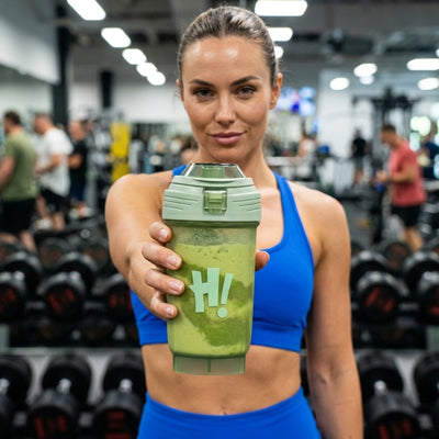 femme sportive tenant shaker vert dans une salle de fitness