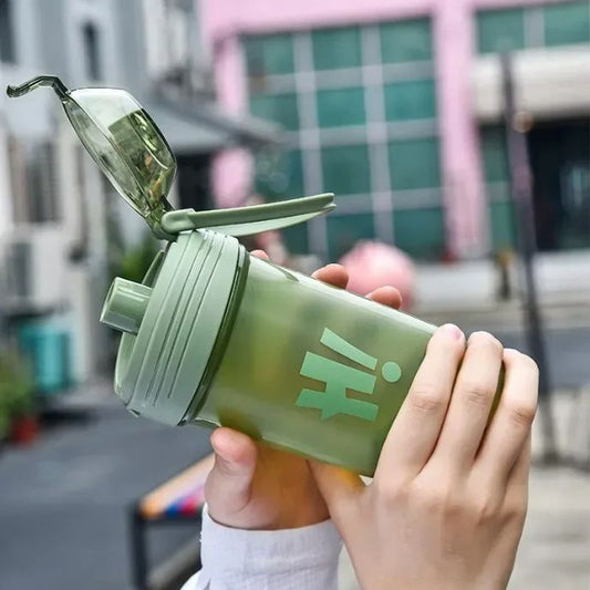 Shaker vert ouvert avec bec verseur visible tenu à deux mains en extérieur
