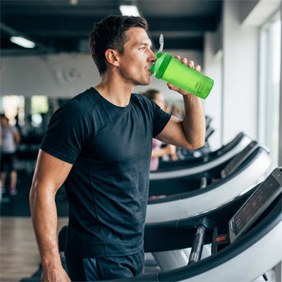 homme boit de shaker vert sur tapis roulant